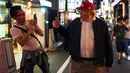 Peniru Presiden AS, Donald Trump mengacungkan jempol ketika seorang pria mengambil foto dirinya selama gelaran KTT G20 di jalanan Osaka, Jepang, Jumat (28/6/2019). Sejumlah pemimpin dunia berkumpul dalam KTT G20 yang berlangsung dua hari di Osaka. (Charly TRIBALLEAU/AFP)