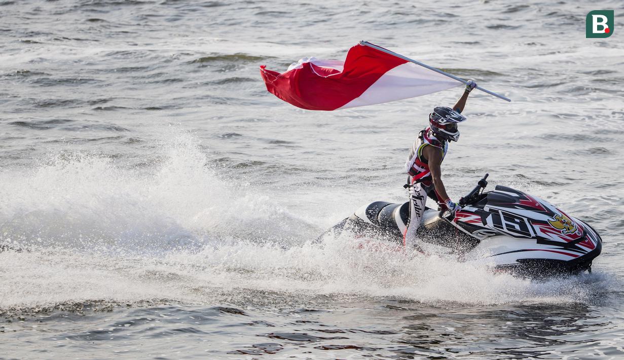 Atlet jetski Indonesia, Aqsa Aswar, mengibarkan bendera merah putih usai meraih medali emas pada nomor endurance runabout open cabang jetski Asian Games XVIII di Jetski Arena Ancol, Jakarta, Minggu (26/8/2018). (Bola.com/Vitalis Yogi Trisna)