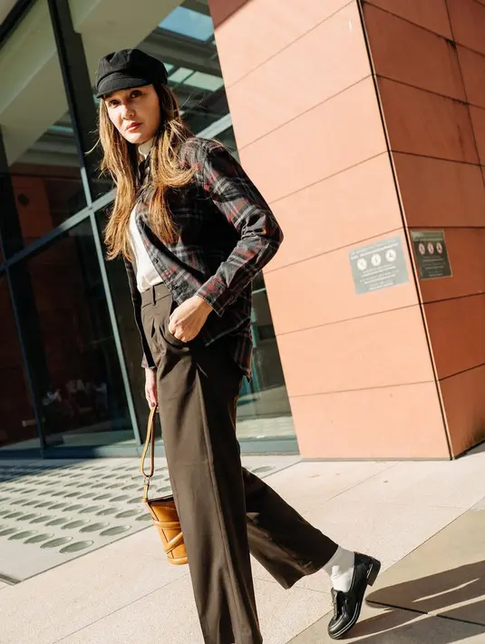 Gaya chic Luna Maya saat liburan dengan layering turtleneck sweater dan flanel. Ia tampak menumpuk sweater turtleneck putihnya dengan kemeja flanel, dipadu dengan celana panjang cokelat tua. Ia menambahkan topi dan loafers hitam. Foto: Instagram.