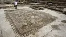 Seorang peneliti sejarah kuno saat ingin membersihkan lantai yang menampakkan gambar - gambar seperti  ikan dan binatang lainnya di Tel Aviv, Israel, Senin (16/11/2015). Tempat ini telah ada pada zaman Romawi dan periode Bizantium.  (REUTERS/Nir Elias)