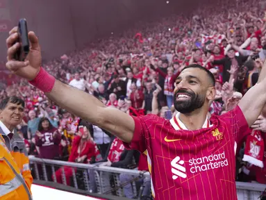 Pemain Liverpool, Mohamed Salah merayakan kemenangan dengan berswafoto bersama dengan para suporter timnya dalam laga lanjutan Liga Inggris 2024/2025 melawan Tottenham Hotspur di Anfiled, Liverpool, Inggris, Minggu (27/04/2025) waktu setempat. (AP Photo/Jon Super)