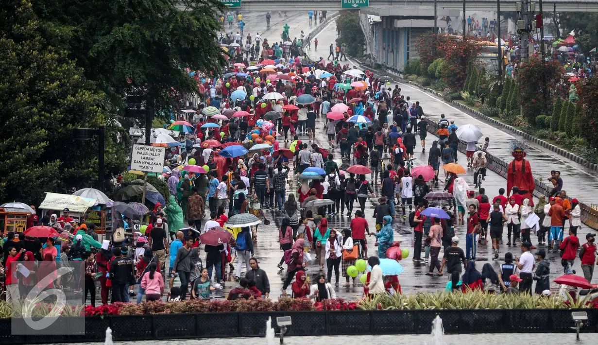 Warga menghadiri Car Free Day di Bundaran HI, Jakarta, Minggu (13/11). Meski gerimis di kawasan tersebut mereka tak surut untuk berolahraga. (Liputan6.com/Faizal Fanani)