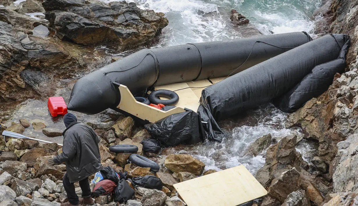 Seorang pria berdiri di samping perahu karet di Thermi di pulau Lesbos Yunani pada 7 Februari 2023. Tiga migran tewas dan lebih dari 20 orang dikhawatirkan hilang setelah perahu kedua tenggelam di lepas pantai Yunani hanya dalam beberapa hari, kata penjaga pantai. (Manolis Lagoutaris / AFP)