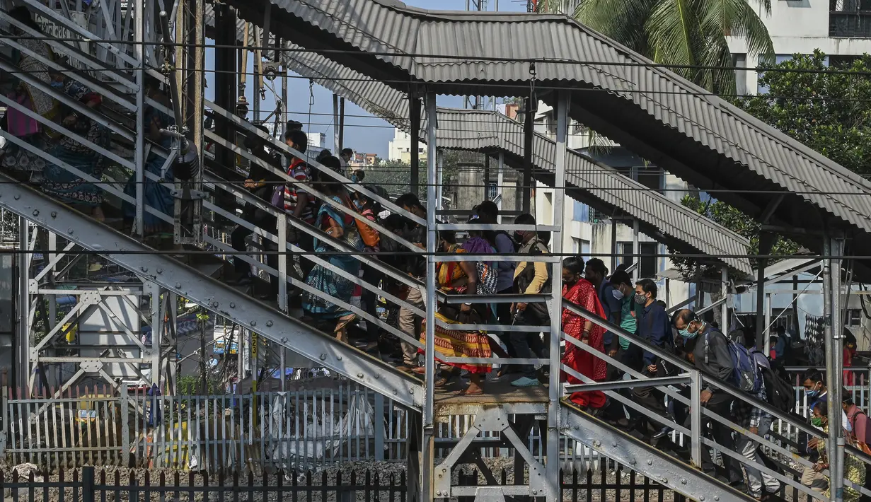 Penumpang menaiki jembatan penyeberangan setelah keluar dari kereta lokal pinggiran kota di Kolkata, India, Senin (1/11/2021). Layanan kereta api kembali normal setelah menerapkan pembatasan yang diberlakukan sebelumnya untuk mengekang penyebaran corona Covid-19. (DIBYANGSHU SARKAR/AFP)