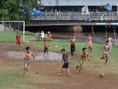 Anak-anak bermain sepak bola di bantaran Kanal Banjir Barat, Jakarta, Jumat (5/4). Tidak adanya lapangan menjadikan lokasi tersebut sebagai tempat bermain mereka, meskipun dalam kondisi seadanya. (Liputan6.com/Immanuel Antonius)