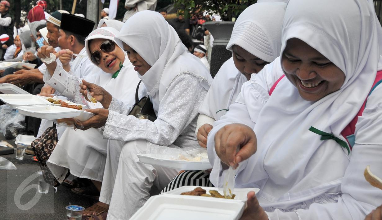 Sejumlah ibu-ibu demonstran beristirahat sambil makan di Jalan Medan Merdeka Selatan, Jakarta, Jumat (4/11). Ratusan ribu massa aksi damai melakukan aksi menuntut penegakan hukum kasus dugaan penistaan agama. (Liputan6.com/Yoppy Renato)