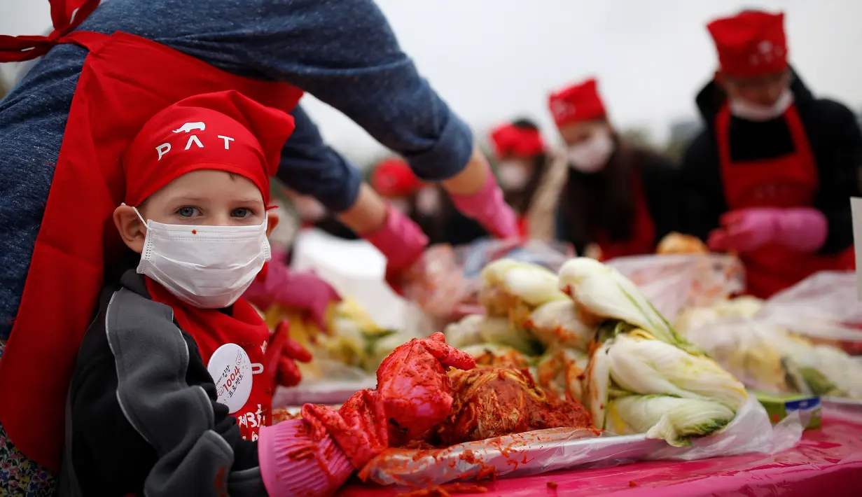 Seorang anak laki-laki ambil bagian membuat Kimchi, hidangan tradisional Korea Selatan, selama Festival Kimchi Seoul di pusat kota Seoul, Jumat (44/11). Kimchi merupakan makanan yang terbuat dari sawi putih atau lobak yang difermentasikan. (REUTERS / Kim 