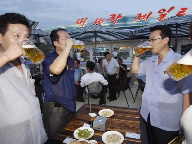 Sekelompok pria minum bir selama festival di Korea Utara. Mereka merayakan janji Kim Jong Un untuk memperbaiki standar hidup dan membangun bangsa (AP)