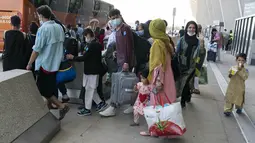 Keluarga dievakuasi dari Kabul, Afghanistan, menunggu untuk naik bus setelah mereka tiba di Bandara Internasional Washington Dulles, di Chantilly, Va, Rabu (25/8/2021). (AP Photo/Jose Luis Magana)
