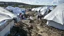Para migran menggali di sekitar tenda setelah hujan badai di kamp pengungsi Kara Tepe, di pulau Lesbos, Yunani (14/10/2020).  Sekitar 7.600 pengungsi dan migran telah menetap di kota tenda baru setelah kebakaran berturut-turut pada tanggal 14 September. (AP Photo/Panagiotis Balaskas)
