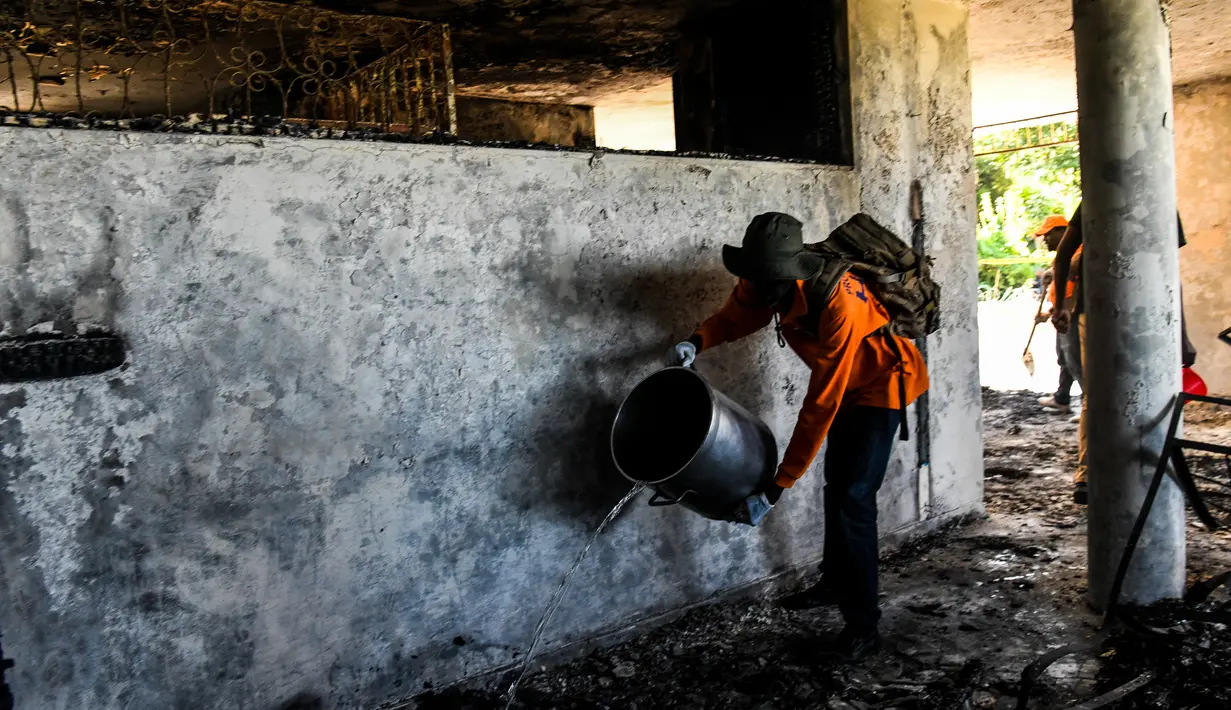 Seorang petugas pemadam kebakaran memadamkan sisa api di dalam Panti Asuhan Church of Bible Understanding, pinggiran Port-au-Prince di ibu kota Haiti, Jumat (14/2/2020). Panti asuhan yang sudah tidak berizin sejak 2013 itu menampung sekitar 66 anak-anak. (CHANDAN KHANNA/AFP)