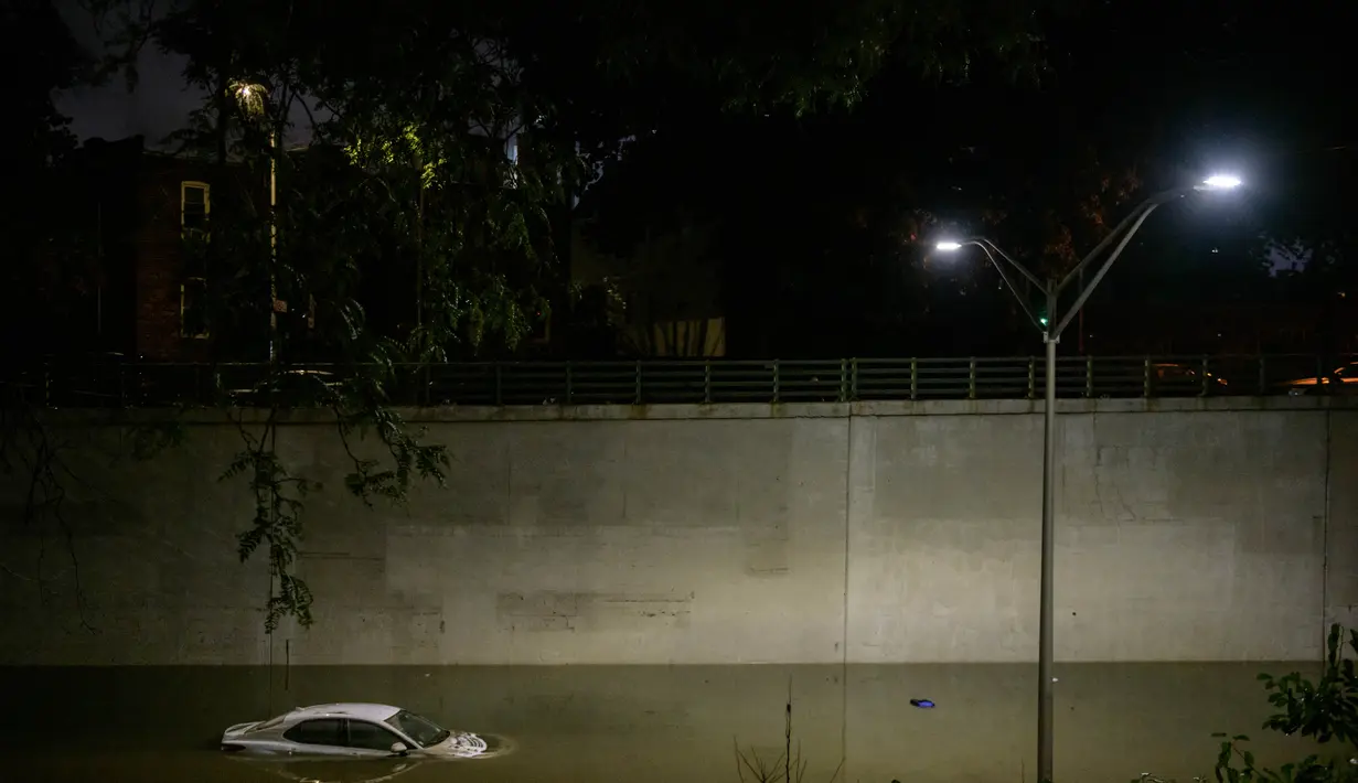 Sebuah mobil terjebak banjir yang merendam jalanan di Brooklyn, New York, Amerika Serikat, Kamis (2/9/2021). Banjir bandang terjadi di sejumlah titik di pusat kota New York setelah hujan lebat yang dipicu Badai Ida mengguyur kota tersebut. (AFP/Ed Jones)