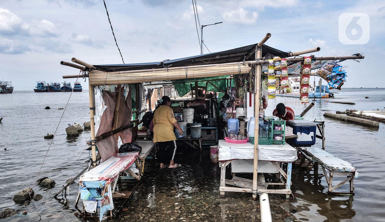 Warga tetap membuka warung meski terendam banjir rob di Pelabuhan Kali Adem, Muara Angke, Jakarta, Kamis (22/10/2020). Banjir akibat air pasang dengan ketinggian mencapai 30 cm tersebut telah merendam kawasan Pelabuhan Kali Adem dan sudah berlangsung selama lima hari. (merdeka.com/Iqbal S. Nugroho)