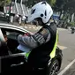 Petugas menilang pengendara mobil berpelat genap yang melintas pada tanggal ganjil di Bundaran Senayan, Jakarta, Rabu (31/8). Sejak kemarin mulai diberlakukan sanksi kepada pengendara yang melanggar aturan ganjil-genap. (Liputan6.com/Gempur M Surya)