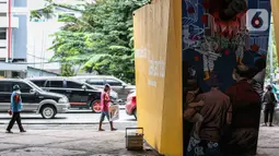 Sejumlah pedagang berjalan di dekat mural imbauan untuk melawan COVID-19 di Jakarta, Kamis (17/11/2020). Menurutnya, capaian tersebut sudah lebih baik, bahkan berada di atas rata-rata tingkat kesembuhan global. (Liputan6.com/JohanTallo)