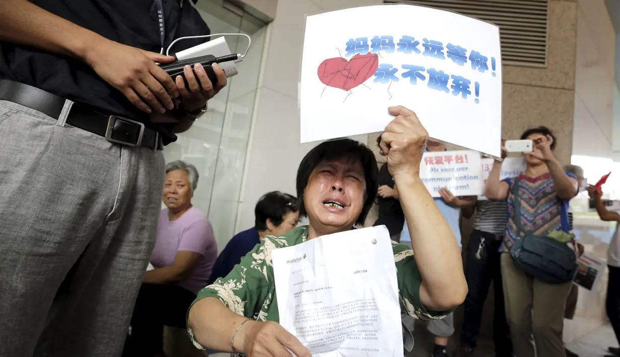 Salah satu keluarga penumpang MH370 menangis saat menggelar aksi di depan kantor Malaysia Airlines, Beijing, China, Kamis (6/8). Pemerintah Malaysia telah resmi menyatakan puing pesawat di Pulau Reunion adalah bagian dari MH370. (REUTERS/Jason Lee)