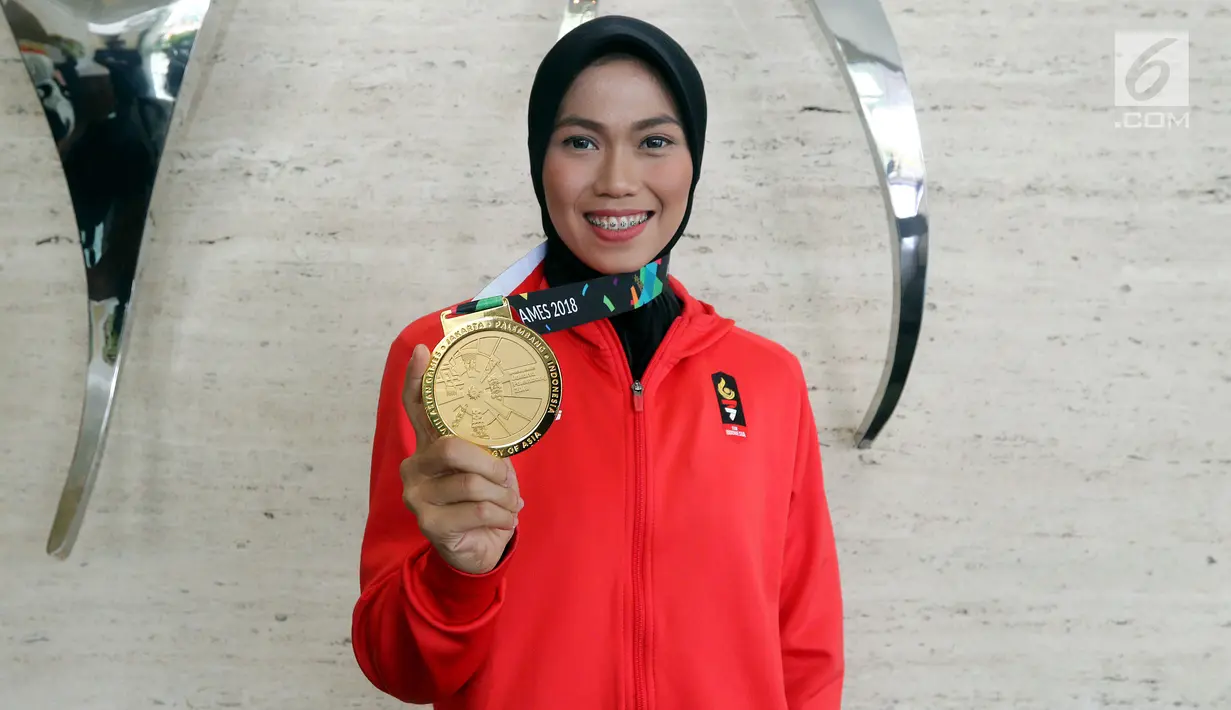 Atlet Taekwondo Defia Rosmaniar menunjukkan medali emas Asian Games 2018 saat berkunjung ke SCTV, Senayan City, Jakarta, Senin (20/8). Kunjungannya tersebut untuk melakukan wawancara. (Liputan6.com/Johan Tallo)