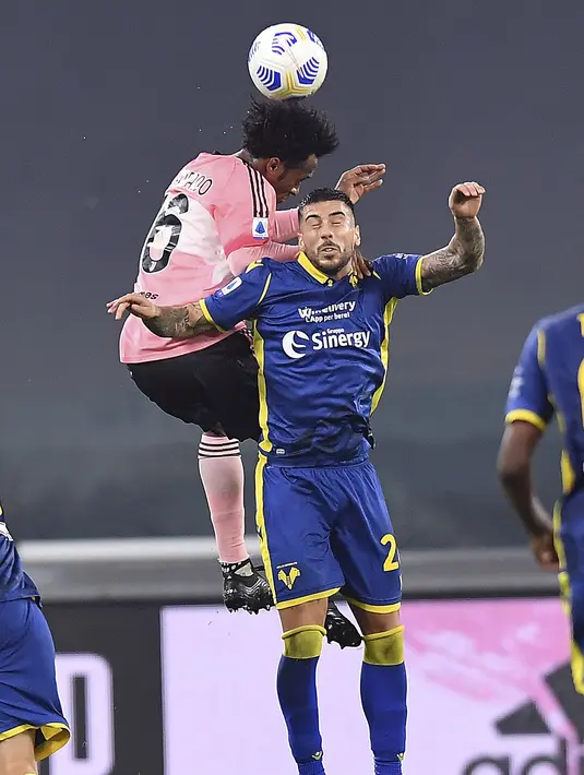 Gelandang Juventus, Juan Cuadrado berebut bola udara dengan pemain Hellas Verona pada pertandigan lanjutan Liga Serie A Italia di Allianz Stadium di Turin (25/10/2020). Juventus bermain imbang 1-1 atas Verona. (Tano Pecoraro/LaPresse via AP)