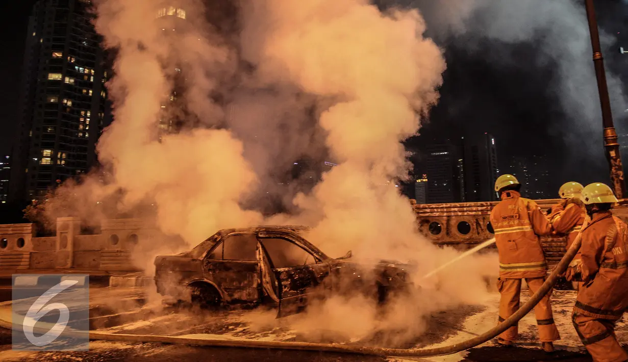 Petugas berusaha memadamkan api mobil yang terbakar di jalan layang Latuharhari, Jakarta, Kamis (18/9/2015). Diduga kebakaran akibat konsleting listrik yang terjadi dibagian depan kap mobil. (Liputan6.com/Faizal Fanani)