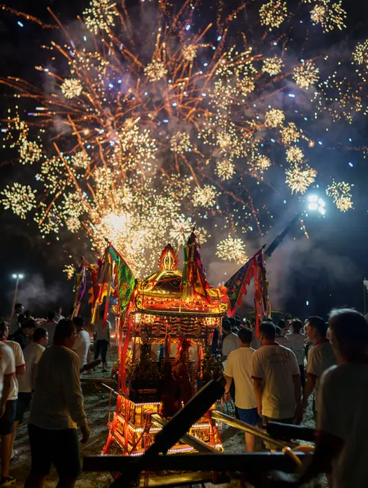Setelah prosesi hari Kamis, parade singkat lainnya diadakan pada malam hari yang berpuncak pada upacara pelepasan di mana tongkang dibakar sehingga arwah yang dikumpulkan dapat secara simbolis berlayar ke alam lain. (AP Photo/Vincent Thian)