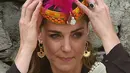 Duchess of Cambridge, Kate Middleton marapikan topi tradisional suku Kalash selama kunjungannya ke Lembah Bumburate di Distrik Chitral utara Pakistan (16/10/2019). Kate Middleton tampil cantik berpenampilan dengan topi tradisional Suku Kalash. (AFP Photo/Farooq Naeem)