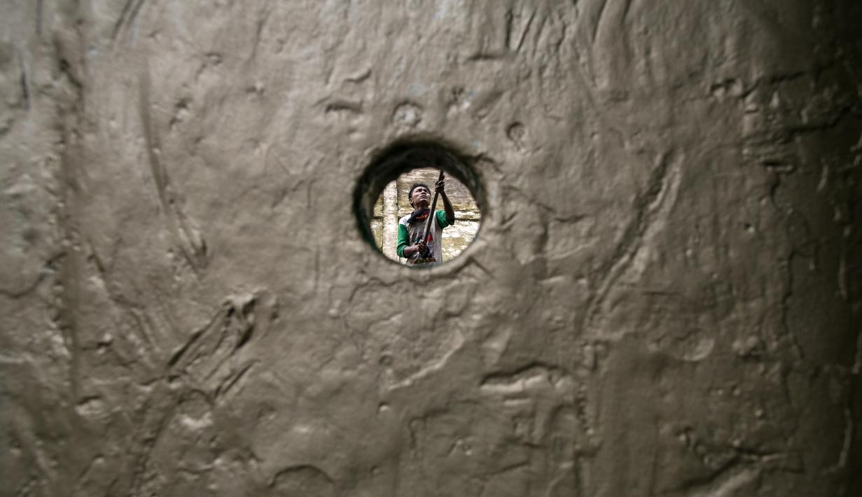 Seorang pekerja saat mengecat sebuah kapal di galangan kapal di tepi Sungai Yangon, yang terletak di pinggiran Yangon, Myanmar (30/7/2019). (AFP Phot/Sai Aung Main)