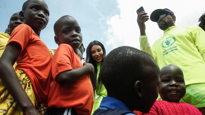 Rapper AS, Kanye West dan istrinya, Kim Kardashian mengunjungi anak-anak yatim di Kampung Anak UWESCO di Masulita, Uganda, Selasa (16/10). Ketika di sana, Kanye West membagikan ratusan pasang Yeezy Boost 350 V2s kepada anak-anak. (STRINGER / AFP)
