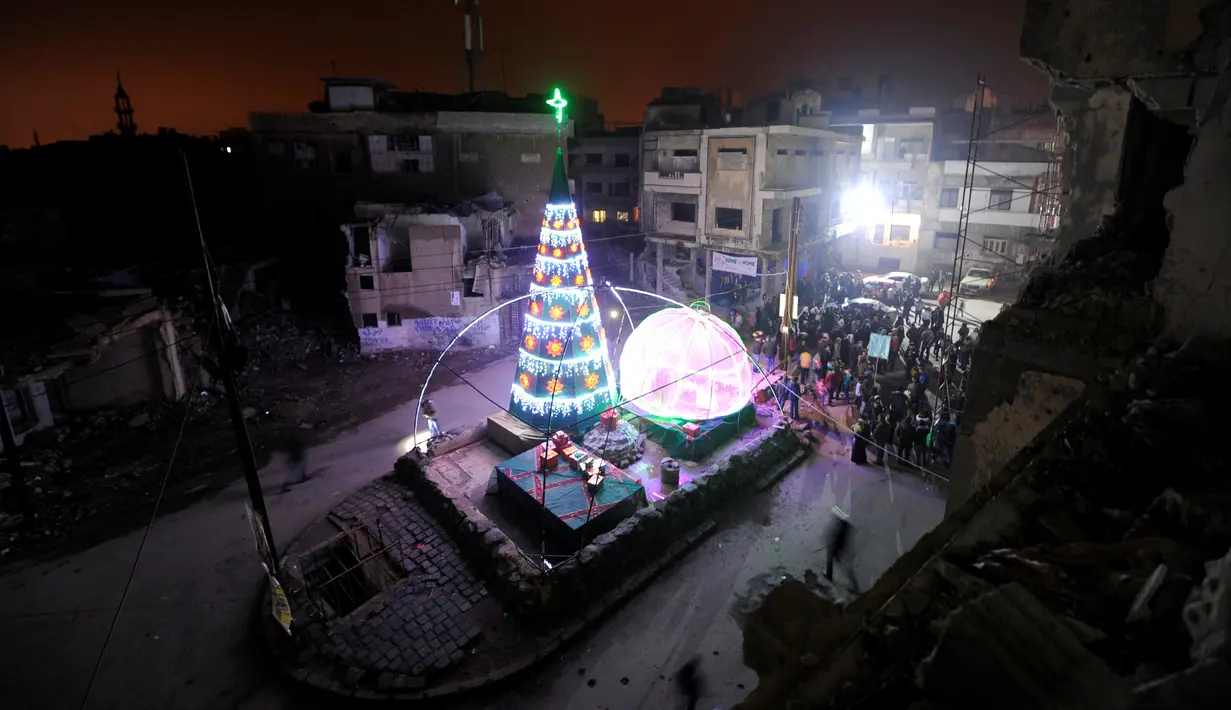 Suasana perayaan malam Natal di kawasan Al-Hamidiyah yang dikelilingi reruntuhan bangunan kota tua Homs, Suriah, (24/12). (REUTERS/Omar Sanadiki)