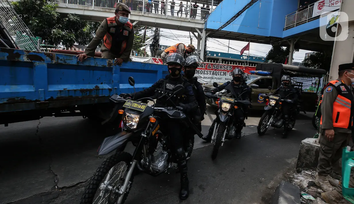 Aparat gabungan melakukan penertiban kepada pedagang yang berjualan di trotoar di kawasan Tanah Abang, Jakarta, Minggu (2/5/2021). Selain merazia barang dagangan pedagang, aparat gabungan juga menegur warga yang tidak menerapkan protokol kesehatan. (Liputan6.com/Johan Tallo)