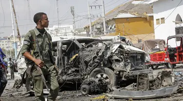 Seorang anggota pasukan keamanan berjalan melewati reruntuhan di lokasi pemboman di Mogadishu, Somalia (13/2/2021). Bom mobil meledak di Mogadishu, Somalia di luar kompleks parlemen dan tak jauh dari Istana Kepresidenan Somalia. (AP Photo/Farah Abdi Warsameh)