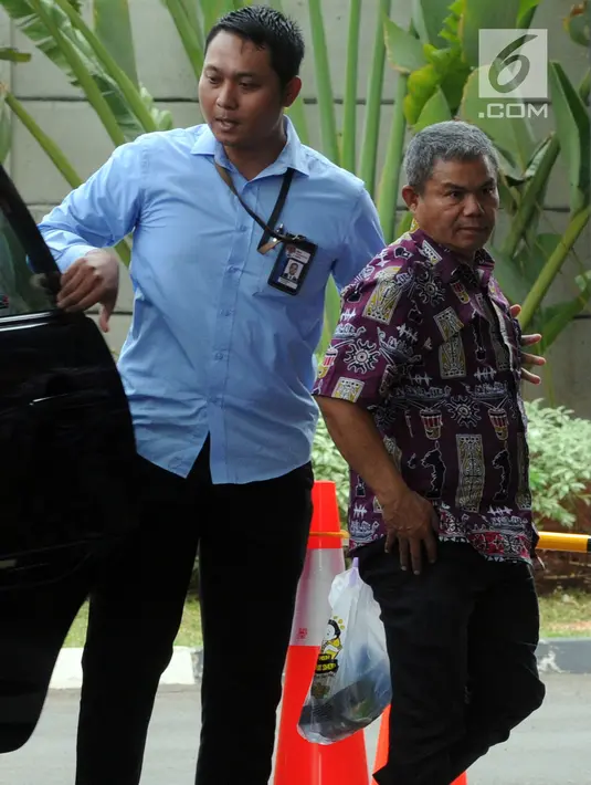 Petugas Pemeriksa Pajak Wilayah Maluku-Papua Sulimin Ratmin (batik) digiring petugas setibanya di gedung KPK, Jakarta, Kamis (4/10). Sulimin Ratmin terjaring OTT KPK di Ambon dan Papua terkait dengan pengurangan pembayaran pajak. (Merdeka.com/Dwi Narwoko)