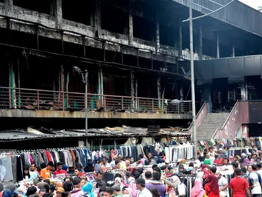 Suasana kerumunan pedagang dan pembeli di depan gedung Pasar Senen pasca kebakaran, Jakarta, Minggu (22/1). Pasca kebakaran tidak membuat para pedangang putus asa, sebagian dari mereka ada yang tetap berjualan. (Liputan6.com/Helmi Affandi)