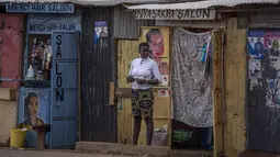 Seorang perempuan berdiri di luar sebuah salon di daerah Kibera di Nairobi, Kenya, Kamis, 11 Agustus 2022. Rakyat Kenya menunggu hasil pemilihan presiden yang berlangsung ketat namun tenang di mana jumlah pemilih lebih rendah daripada biasanya. (AP Photo/Ben Curtis)