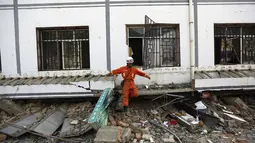 Salah satu anggota tim penyelamat keluar dari gedung yang rusak akibat gempa di Longtoushan, provinsi Yunan, Tiongkok, (6/8/2014). (REUTERS/Stringer)