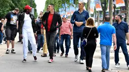 Sejumlah pria tertinggi di dunia berjalan di tengah keramaian di Champs-Elysees Avenue, Paris, 1 Juni 2018. Belasan pria tertinggi di dunia bertemu pada akhir pekan di ibu kota Prancis. (AFP/GERARD JULIEN)