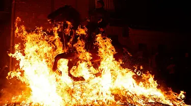 Seorang pria menunggangi kuda melewati api unggun saat festival Luminarias di San Bartolome de Pinares, Spanyol, Jumat (16/1/2020). Festival tersebut digelar setiap tahunnya, sehari sebelum perayaan Santo Antonius yang merupakan pelindung binatang. (AP Photo/Manu Fernandez)