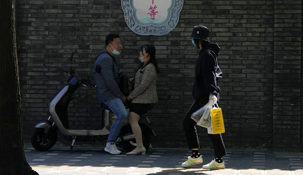 <p>Warga yang memakai masker melewati slogan "Kesetaraan" di Beijing, China, Selasa (3/5/2022). China telah berpegang teguh pada pendekatan ketat 'Nol COVID' yang membatasi perjalanan, menguji massal seluruh kota, dan mendirikan fasilitas sementara yang luas untuk mencoba mengisolasi setiap orang yang terinfeksi. (AP Photo/Ng Han Guan)</p>