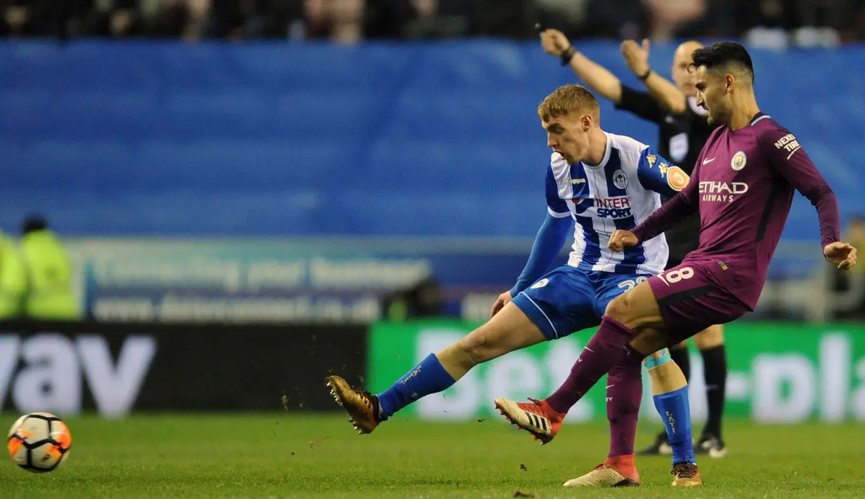 Pemain Manchester City, Ilkay Gundogan berusaha mencetak gol dengan kawalan pemain Wigan Athletic, Jay Fulton pada babak kelima Piala FA 2017-2018 di DW Stadium, Senin (19/2). Manchester City menyerah 0-1 dari Wigan Athletic. (AP/Rui Vieira)
