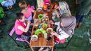 Pengunjung menikmati makan siang sambil digigit ikan dikakinya di restoran kolam ikan di desa Wedomartani di Yogyakarta (15/11/2019). Restoran unik ini dikenal dengan nama Soto Cokro Kembang. (AFP Photo/Oka Hamied)
