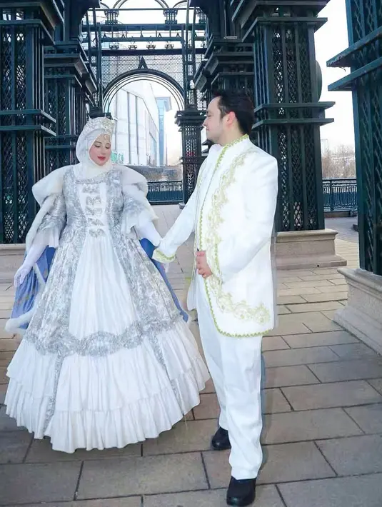 Tasyi Athasyia terlihat anggun dalam ball gown putih bergaya Victorian yang berenda silver. Gaun ini berlapis cape satin berbulu warna sky blue [@tasyiiathasya]