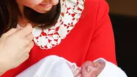 Duchess of Cambridge, Kate Middleton menggendong bayi ketiganya ketika akan meninggalkan Rumah Sakit St Mary's di Paddington, London, Senin (23/4). Kate yang memakai baju merah menggendong si kecil yang berselimut kain putih. (John Stillwell/Pool via AP)