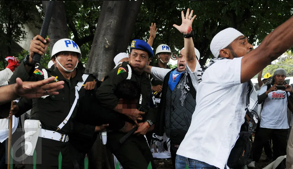 Polisi Militer Angkatan Laut menangkap seorang pria yang diduga provokator dalam aksi damai 2 Desember di kawasan Monas, Jakarta, Jumat (2/12). Pria ini sempat dipukuli hingga mengalami luka di bagian kepala. (Liputan6.com/Gempur M Surya)