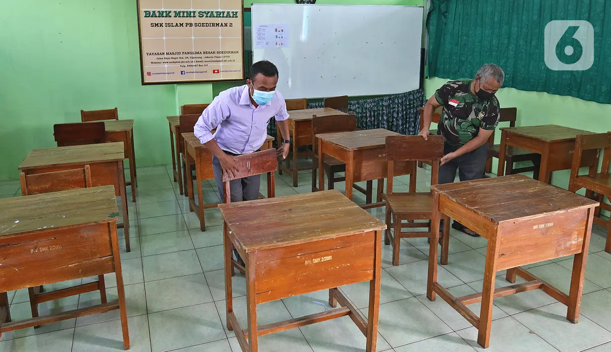 Petugas merapikan meja dan kursi jelang dibukanya pembelajaran tatap muka di SMK PB Soedirman 2, Jakarta, Selasa (6/4/2021). Uji coba pembelajaran tatap muka akan dilakukan di 5 madrasah, 1 PKBM, 42 SD, 13 SMP, 9 SMA, dan 30 SMK. (Liputan6.com/Herman Zakharia)
