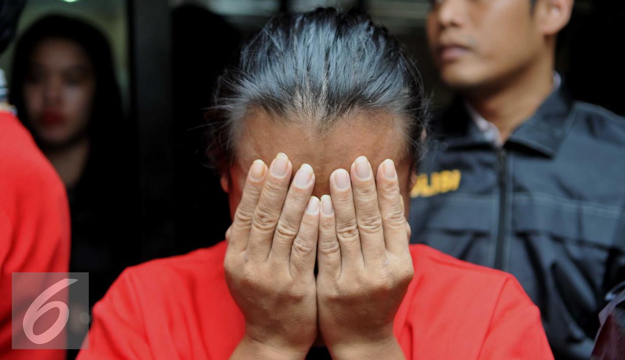 Tersangka MS menutupi wajahnya ketika dihadirkan dalam rilis di Polres Jakarta Pusat, Selasa (17/11). Polres Jakpus berhasil menangkap 2 pelaku perdagangan manusia (human traficking) dengan iming-iming bekerja sebagai PRT. (Liputan6.com/Gempur M Surya)