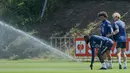 (kiri-kanan) Pemain Jerman Antonio Ruediger, Leroy Sane, dan Julian Brandt bermain dengan sprinkler saat sesi latihan di pusat olahraga BVSC, Budapest, Hungaria, 13 Juni 2022. Jerman akan menghadapi Italia pada pertandingan sepak bola UEFA Nations League. (Attila KISBENEDEK/AFP)