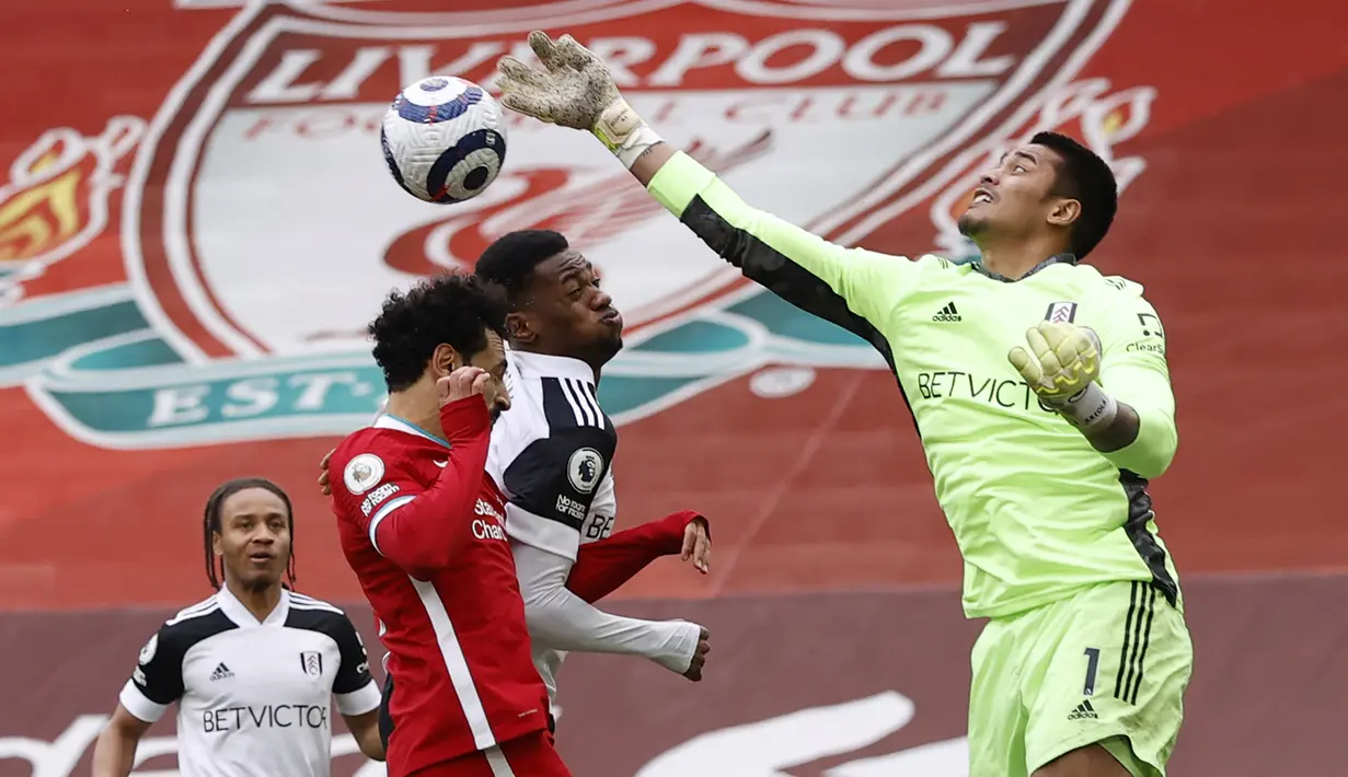 Kiper Fulham, Alphonse Areola (kanan) menepis bola dari ancaman gelandang Liverpool, Mohamed Salah dalam laga lanjutan Liga Inggris 2020/21 di Anfield Stadium, Minggu (7/3/2021). Fulham menang 1-0 atas Liverpool. (AFP/Phil Noble/Pool)