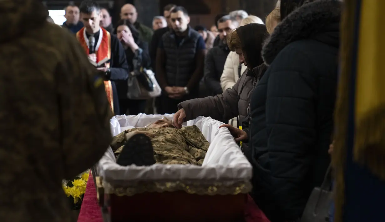 Ibu dari tentara Simakov Oleksandr (41) membelai wajah sang anak saat upacara pemakamannya, setelah dia meninggal dalam aksi, di Gereja Rasul Suci Petrus dan Paulus di Lviv, Ukraina barat, Senin, 4 April 2022. (AP Photo /Nariman El-Mofty)