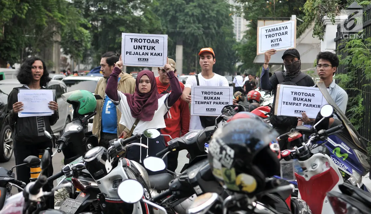 Koalisi Pejalan Kaki membawa poster saat menggelar aksi Tamasya Trotoar Kita di lokasi parkir liar sepanjang jalur pedestrian Gelora Bung Karno (GBK), Jakarta, Minggu (9/12). (Merdeka.com/Iqbal S. Nugroho)