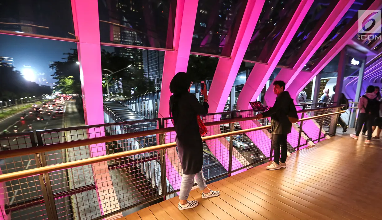 Sepasang remaja foto di atas Jembatan Penyeberangan Orang (JPO) Gelora Bung Karno di Jalan Jend Sudirman, Jakarta, Senin (4/3) malam. JPO tersebut baru saja diresmikan Gubernur DKI Jakarta Anies Baswedan. (Liputan6.com/Fery Pradolo)