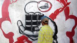 Seniman Yaman, Alaa Rubil, menggunakan bangunan-bangunan yang penuh dengan peluru di kampung halamannya sebagai kanvas, melukiskan gambar kematian dan keputusasaan untuk menyoroti kengerian dan korban perang. (Saleh Al-OBEIDI / AFP)